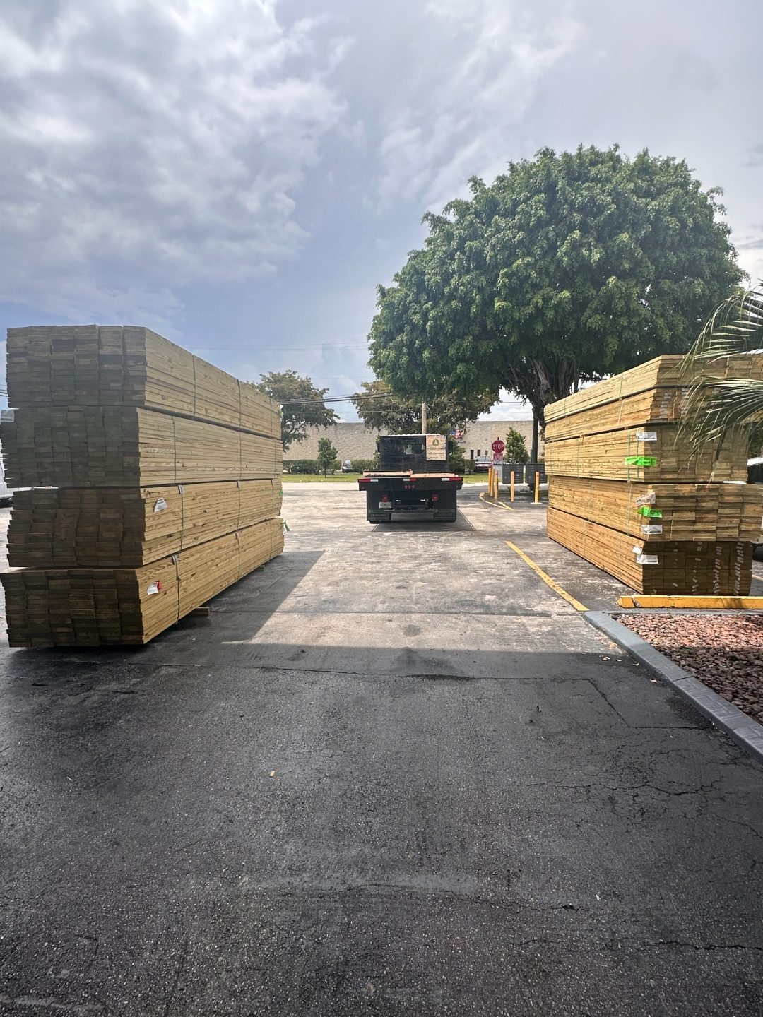 Large stacks of pressure treated lumber flanking a flatbed delivery truck at International Plywood yard
