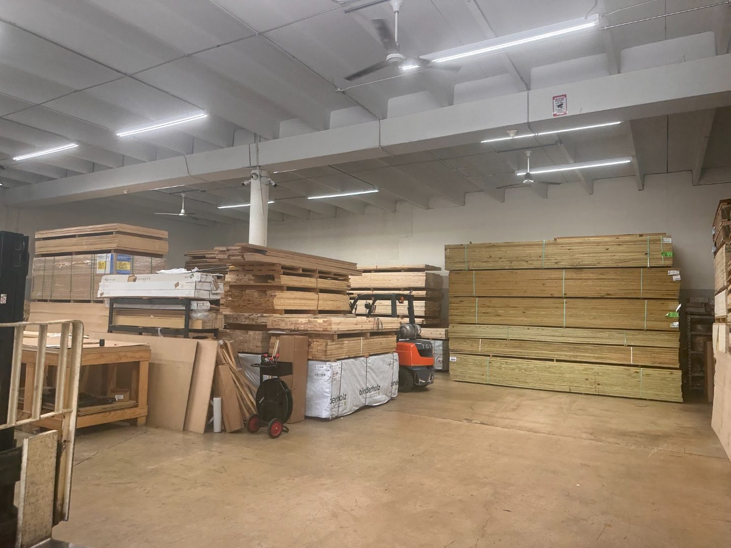 Interior of International Plywood warehouse showing pressure treated lumber stacks and orange Toyota forklift